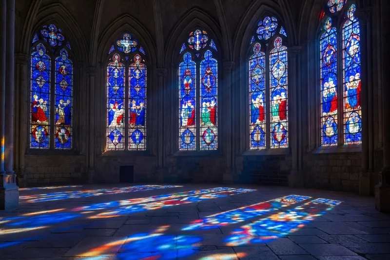 Vitraux du déambulatoire de Chartres au soleil de fin d'après-midi, bleu profond du XIIIe siècle inondant le sol de dalles