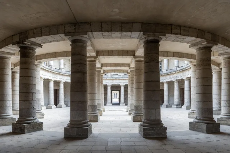 Vue intérieure de la Saline royale d'Arc-et-Senans : ateliers en hémicycle convergeant vers la maison du directeur, colonnes doriques rustiquées